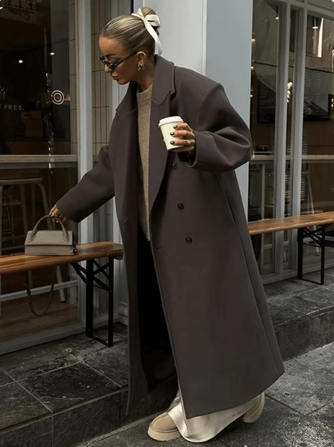 "Manteau long classique femme hiver élégant avec col imposant, coupe ajustée, couleur neutre, idéal saisons froides."