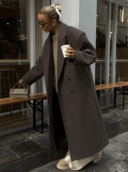 "Manteau long classique femme hiver élégant avec col imposant, coupe ajustée, couleur neutre, idéal saisons froides."